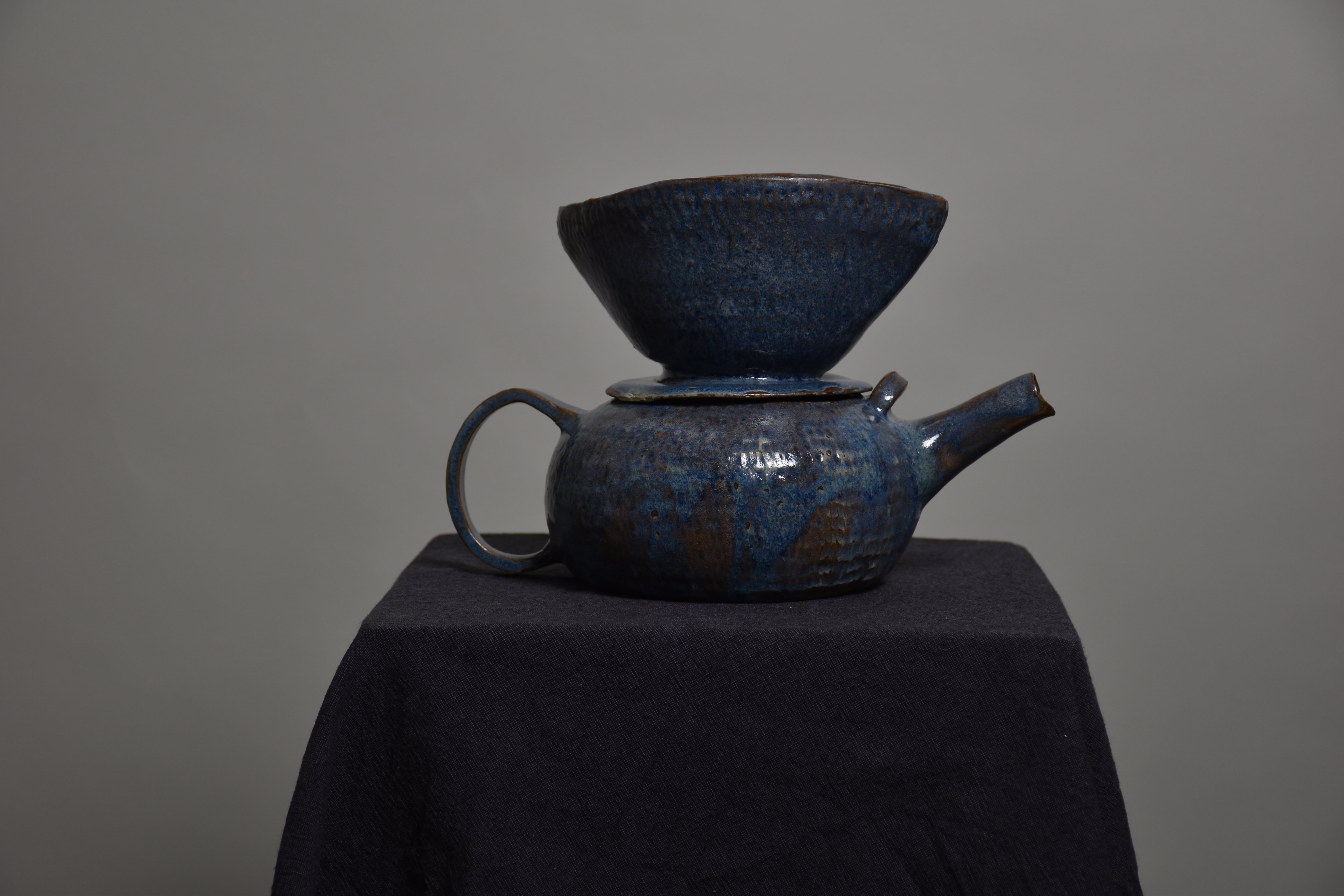 a ceramic, blue coffe pot with filter holder on top of it